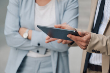 Business people having conversation and using digital tablet outdoors