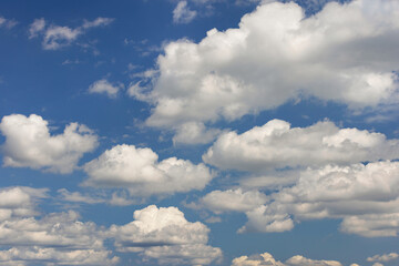 Fluffy white clouds scattered across bright blue sky with sunlight shining through, creating a peaceful atmosphere, serene sky concept