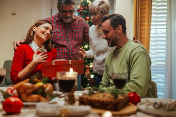 Family giving christmas gift at dinner table