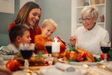 Happy family enjoying christmas dinner together while opening gifts