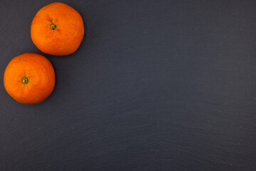 Fresh mandarin citrus fruits on black stone background. Top view. Free copy space.
