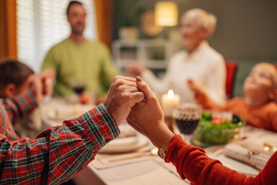 Family holding hands while praying before christmas dinner