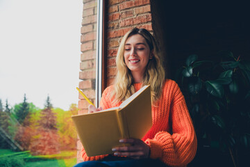 Photo of nice young girl sit windowsill write notebook wear orange clothes enjoy modern cozy interior flat indoors