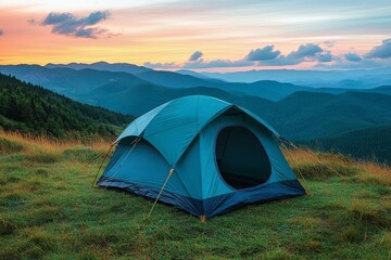 A tent set up on a grassy hilltop with stunning sunset views over mountains
