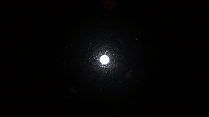 The surface is black and there is a circular light coming out from the center of the image.