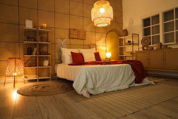 Interior of dark bedroom with cozy bed and glowing lamps