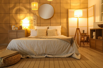 Interior of dark bedroom with cozy bed and glowing lamps