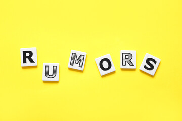 Word RUMORS on yellow background. Gossip concept