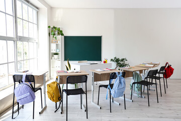 Interior of empty classroom with school desks and clean chalkboard