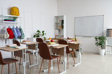 Interior of empty classroom with school desks and clean whiteboard