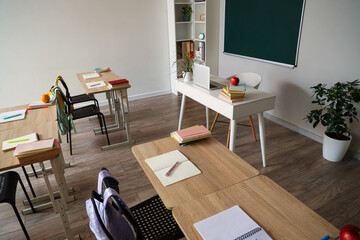 Interior of empty classroom with school desks and clean chalkboard