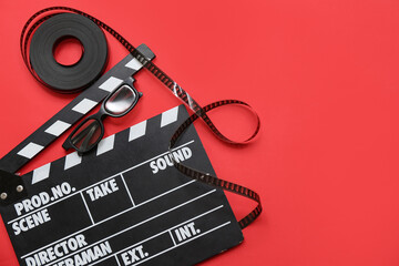 Movie clapper with film reel on red background