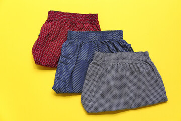 Stylish male trunks on yellow background