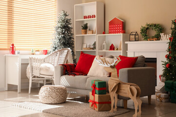 Cozy sofa and workplace with Christmas decor in interior of living room