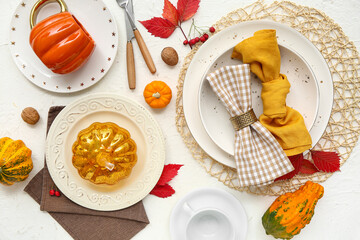 Beautiful table setting with pumpkins, rose hip berries, walnuts and autumn leaves on white background