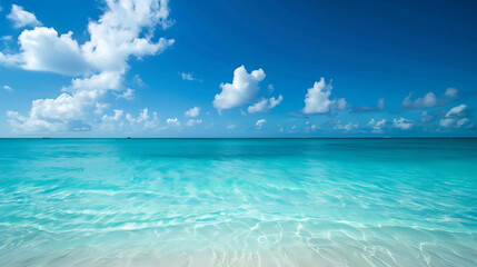 Fototapeta premium Amazing crystal clear blue ocean water with white sand beach and beautiful fluffy clouds in the bright blue sky.