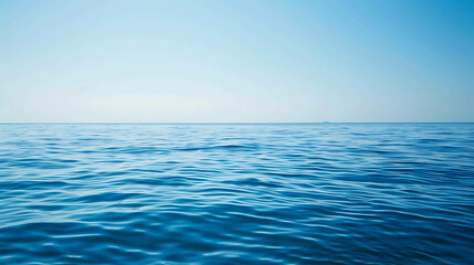 Obraz premium Deep blue ocean with a clear blue sky and a distant ship on the horizon. The water is calm and serene, with gentle waves rippling across the surface.
