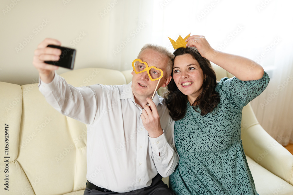 Wall mural husband and wife having fun together. selfie with accessories. party props