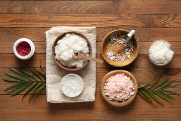 Composition with natural body scrubs, ingredients and palm leaves on wooden background