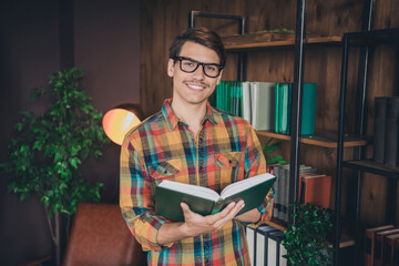 Photo of young nice smart man wear checkered shirt hold book indoors college university library