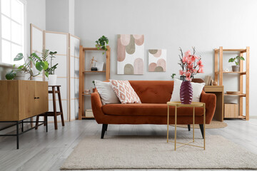 Interior of living room with sofa and magnolia flowers in vase on coffee table