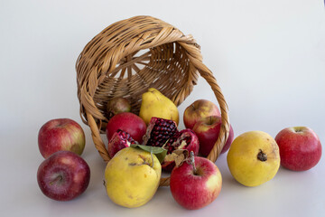 quince, apple, pomegranate, white background in the wicker basket. autumn