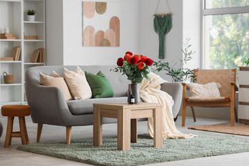 Dahlia flowers on coffee table near cozy sofa in interior of living room