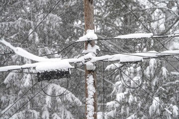 Utility pole and wires covered with snow in blizzard