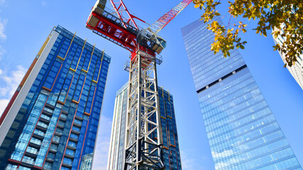 Crane on the construction site in a site surrounded by the high buildings.