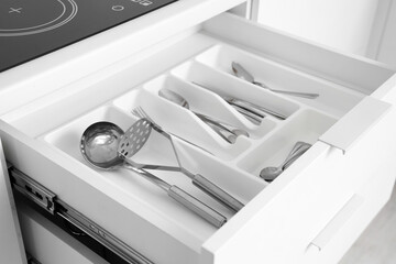 Open drawer with utensils in kitchen, closeup