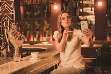 Photo of young lady selfie photo send air kiss dressed white t-shirt sit bar counter cafe lifestyle nightlife holiday vacation interior