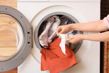 Woman putting dirty laundry into washing machine, closeup