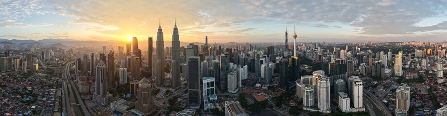 Wide aerial panorama view of Kuala Lumpur skyline with sun shining from behind buildings. Drone...