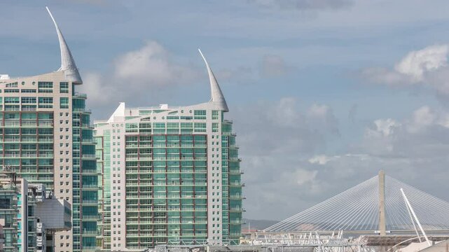 The Parque das Nacoes (Park of Nations) modern neighborhood with skyscrapers aerial timelapse in Lisbon. Vasco da Gama bridge on a background. Clouds passing by. Portugal