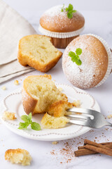 Fresh baked vanilla cinnamon bitten muffin icing sugar powder on retro plate as sweet dessert. Yummy muffins with dessert fork on light marble table