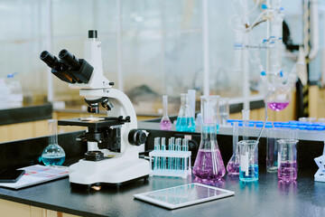 Modern laboratory featuring microscope surrounded by beakers, test tubes, and other scientific apparatus, suggesting ambiance of advanced scientific research