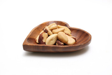 白背景の木製の皿にのせたブラジリアンナッツ