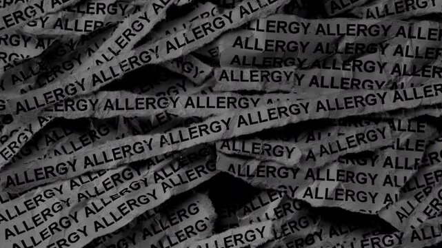 Strips of newspaper with the words Allergy typed on them. Black and white. Close up.