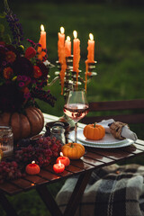 Elegant autumn decoration. Private wedding party for two, table set with floral decor, pumpkins, wine in field or meadow. Fall vibes, sunset, golden hour. Romantic surprise, marriage proposal