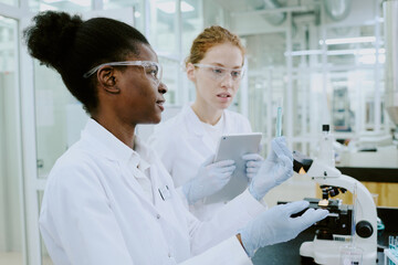 Scientists in laboratory coats performing examination using advanced equipment. Collaborative...