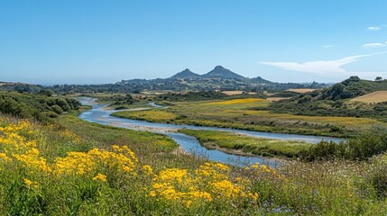 A winding river flows through a valley, with yellow wildflowers in the foreground and mountains in the distance.