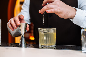 Expert bartender preparing a cocktail with precise measurements at a bar