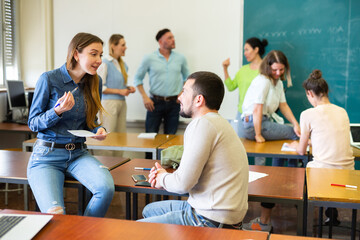 Positive adult students communicating during recess between lectures in classroom