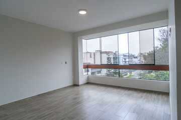 Obraz premium moderna sala de departamento con amplia ventana con vista a la calle, piso de melamina y bien iluminado