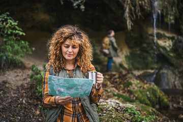 wife hold map and cup explore forest and find route on map