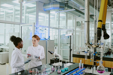 Scientists in white lab coats discussing experimental results in modern, well-equipped laboratory...