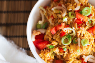 Close-up of a bowl filled with savory rice and tender meat, topped with fresh tomato chunks and sliced scallions that give it a touch of color and flavor