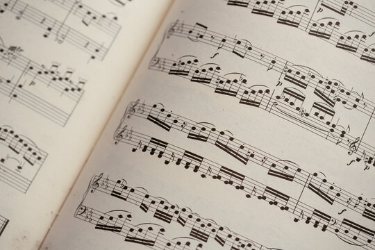 An open sheet music book displaying classical notation and melodies in a lit setting during a quiet afternoon