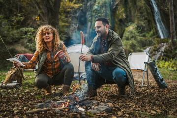 hiker couple enjoy on the camp while grill sausage in front tent