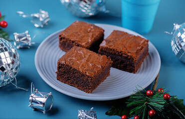 Dark chocolate brownie cakes in a plate on a blue background for Christmas holidays